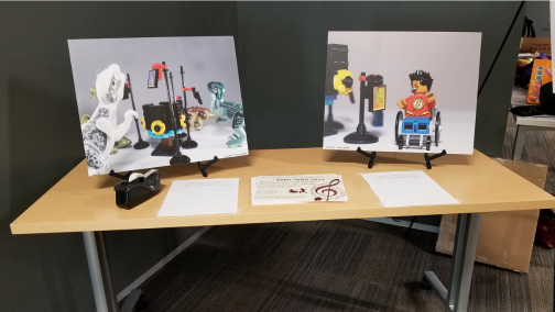 Tami Albin's images of AUMI-themed LEGOs and papers sit on table near event entrance